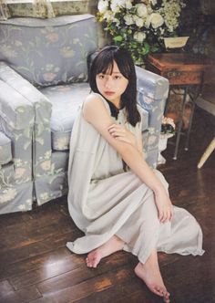 Woman with long hair in a sleeveless dress sitting on a wooden floor indoors