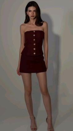 Woman in a dark red strapless top and mini skirt posing in a studio