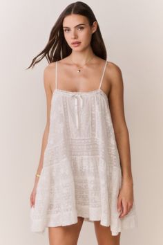 Woman in a white lace dress with a heart necklace, standing indoors