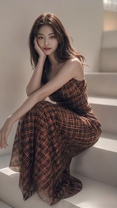 Woman with long hair in a plaid strapless dress sitting indoors