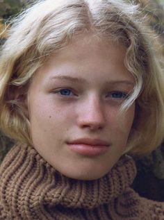 Close up portrait of a young person with blonde hair and blue eyes wearing a turtleneck