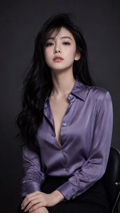 Woman with long black hair wearing a purple satin shirt with open buttons