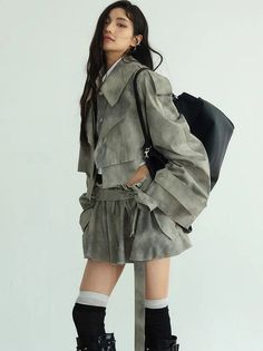 Woman with long hair wearing a cropped jacket and shorts with a black bag