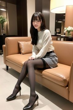 Woman with long black hair wearing a mini skirt and black stockings on a couch