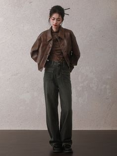 Woman in a brown leather jacket and wide leg jeans with hair sticks in her bun