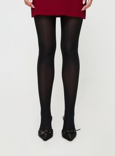 Person wearing black tights, a red dress, and black heels on a white background