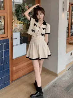 Woman in a cream crop top and pleated skirt posing outdoors