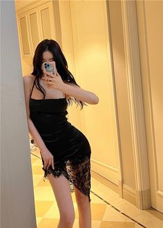 Woman in a black dress with lace trim taking a mirror selfie