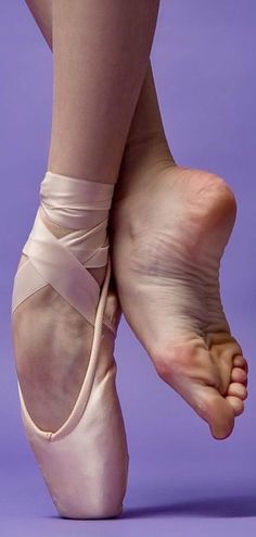 Close up of a person's feet, one in a ballet pointe shoe and the other bare