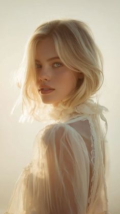 Blonde woman in a white sheer dress with lace trim, looking over her shoulder