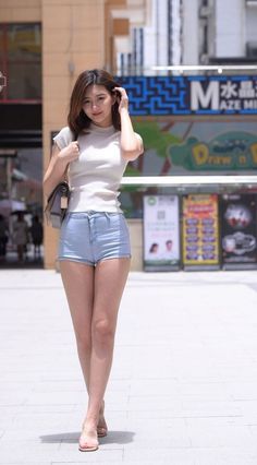 Woman in denim shorts and a white top walking on a street