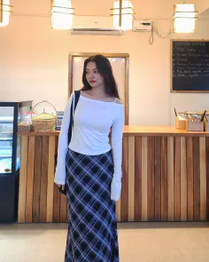 Woman in a white top and plaid skirt standing in a bakery