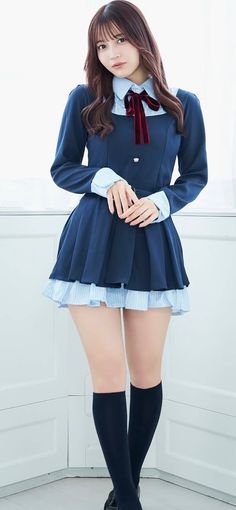 Woman in a dark blue school uniform dress with a red bow and knee-high socks