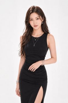 Woman in a black ruched dress with a high slit and jewelry in a studio