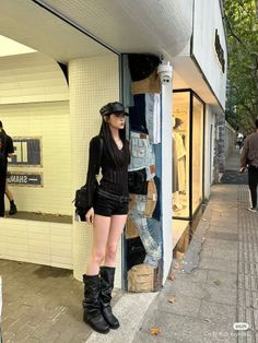 Woman in a black outfit with a leather hat and boots on a street