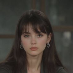 Woman with long dark hair and bangs wearing heart-shaped earrings