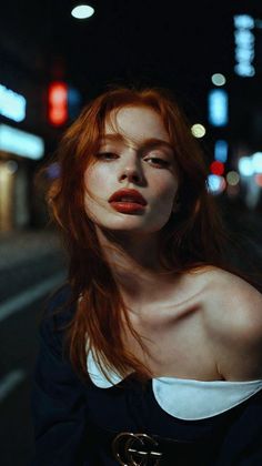 Woman with red hair and red lipstick on a city street at night