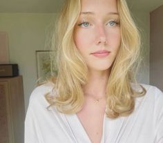 Blonde woman with blue eyes and freckles wearing a white shirt indoors