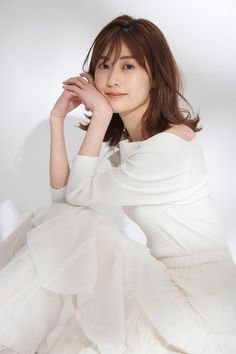 Woman in a white top and skirt posing against a white background