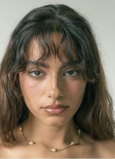 Woman with long dark hair and a nose ring wearing a delicate necklace