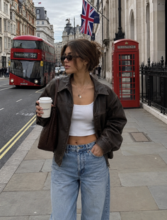Woman in a brown leather jacket and blue jeans on a London street
