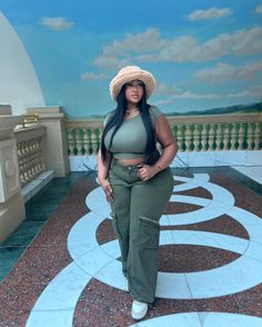 Woman in a green crop top and cargo pants with a fuzzy bucket hat indoors