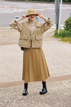 Woman in a khaki outfit with a bucket hat and pleated skirt outdoors
