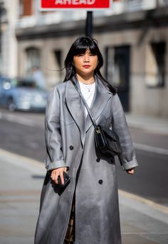 Woman in a long gray coat and shoulder bag on a city street