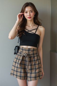 Woman with long hair wearing a black crop top and plaid shorts indoors