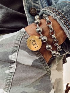 Close up of a person's arm wearing silver bracelets and a 'MOM' charm