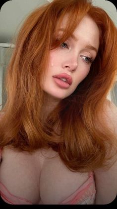 Woman with red hair and a pink bra, with a teardrop on her cheek