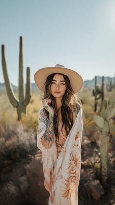 Woman with long hair and a hat in a desert landscape with cacti