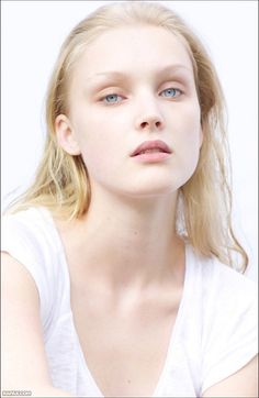 Blonde woman with blue eyes wearing a white t-shirt, looking directly at the camera