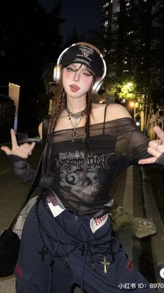 Woman with braids and headphones wearing a sheer top and cross jewelry at night