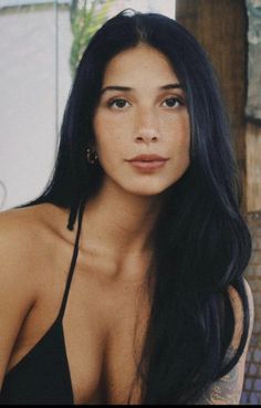 Woman with long black hair wearing a black bikini top, looking at the camera