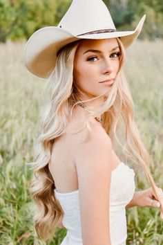 Woman with long blonde hair and a cowboy hat in a field