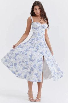 Woman in a white and blue floral dress with a slit, posing on a white background