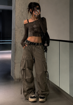Woman in a crop top and cargo pants taking a mirror selfie indoors