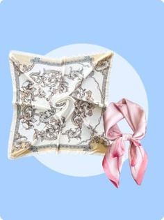 Two silk scarves, one with a baroque pattern and one pink, on a light blue background