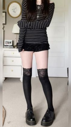 Person in a striped shirt, black shorts, and thigh-high lace socks indoors