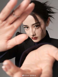 Woman in a black suit with hands reaching towards the camera