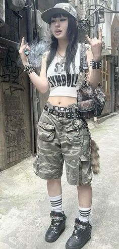 Person in camouflage shorts and a crop top with a cigarette on a street