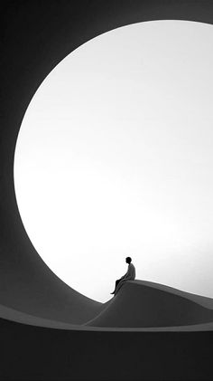 Minimalist black and white image of a solitary figure sitting on an abstract landscape