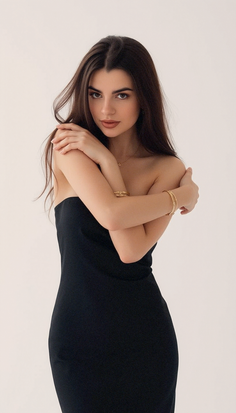 Woman with long dark hair wearing a black strapless dress and jewelry