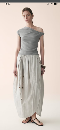 Woman in an off-shoulder top and a long pleated skirt with sandals