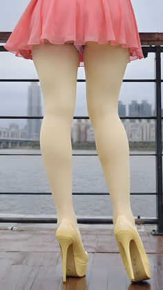 Person in a pink skirt and high heels standing by a river with a cityscape