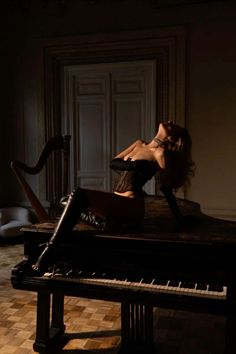 Woman in a corset and thigh-high boots posing on a piano in a dimly lit room