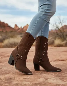 Person wearing brown cowboy boots and jeans in a desert landscape