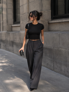 Woman in a black crop top and wide leg pants walking on a street