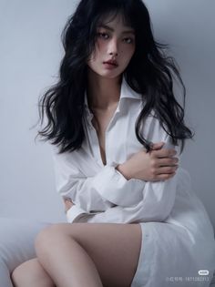 Woman with long black hair wearing an unbuttoned white shirt indoors